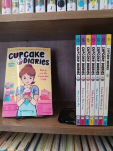 Book Cover for 1st Cupcake Diaries Graphic Novel, and the spines of books 2 through 8