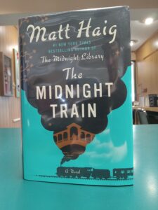 Cover for 'The Midnight Train', showing a train spewing black smoke, with the image of a couple on a bridge inside the smoke