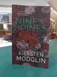 Cover for the novel 'Nine Pines', featuring an illustration of red, white, and blue flowers