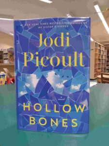 Photo of the cover for the novel 'Hollow Bones', featuring a blue mosaic pattern that reveals a sky behind it