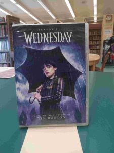Photo of the case for the DVD set 'Wednesday Season 1', featuring Wednesday Addams holding a black umbrella in the rain